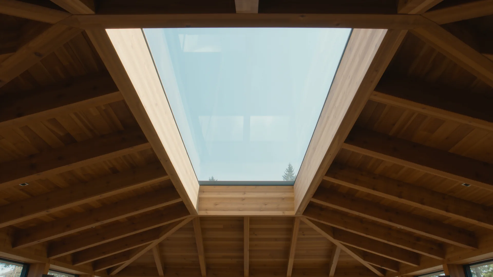 Dachstuhl aus hellem Holz von innen, Licht fällt durch ein Dachfenster