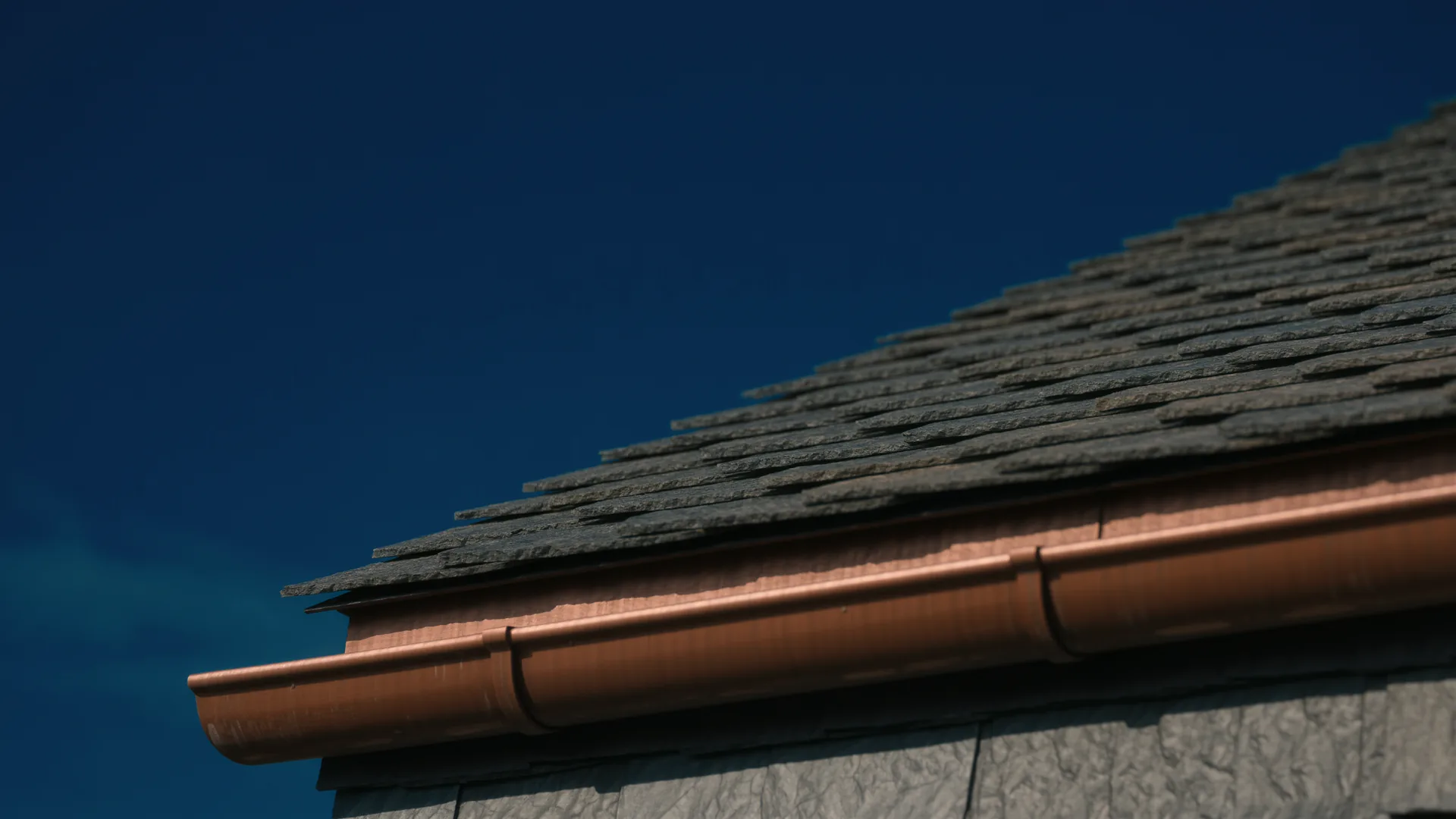 Schieferdach mit Kupferrinne vor dunkelblauem Himmel